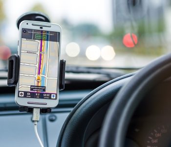 Smartphone on a car dashboard showing a navigation map screen, illustrating Driving Apps for route guidance.