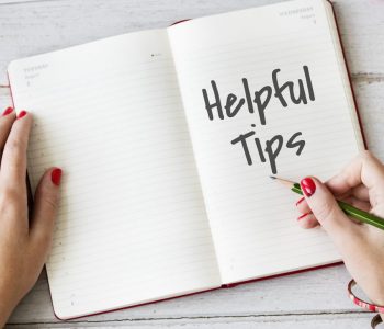 Hands holding a pencil above an open notebook with “Helpful Tips” written, representing advice from a credit assessor on improving financial habits and achieving Good Credit.