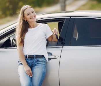 Smiling woman leaning against a silver car holding keys — highlighting Car Colour choice.