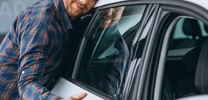 A man rests on a car door, representing Carcoop's car subscription services.