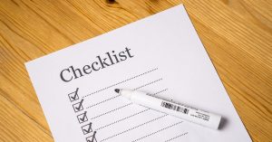 End a Car Lease Early checklist showing a paper with checked boxes and a white marker on a wooden table.