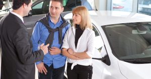 End a Car Lease Early by discussing lease options with a car dealership representative beside a white car.