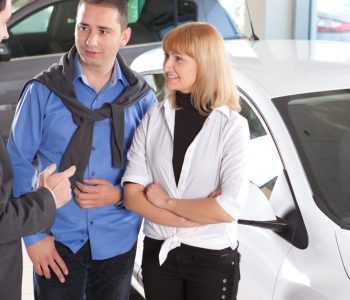 End a Car Lease Early by discussing lease options with a car dealership representative beside a white car.